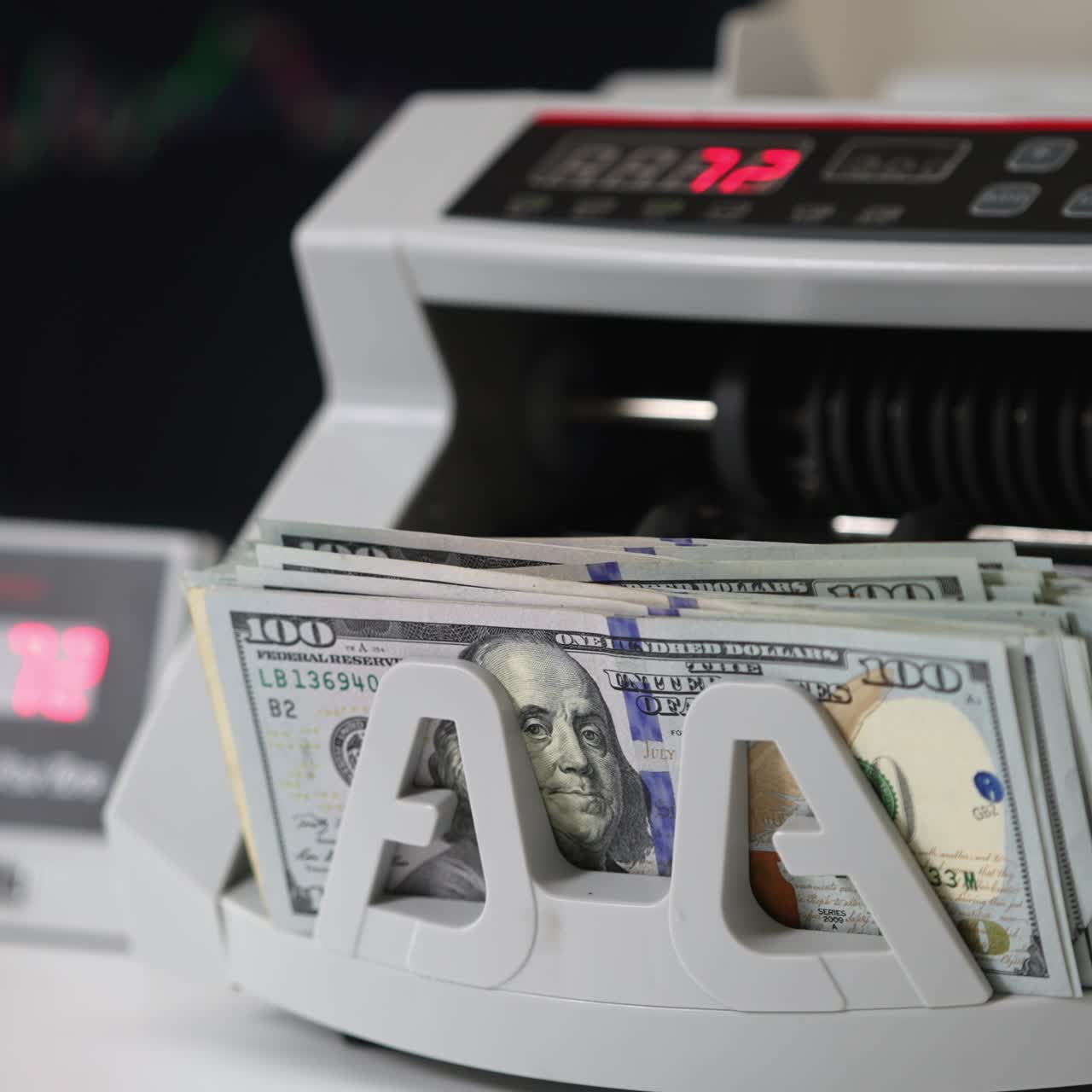 White compact cash counting machine working. One hundred dollar bills being turned in the counter. Close up