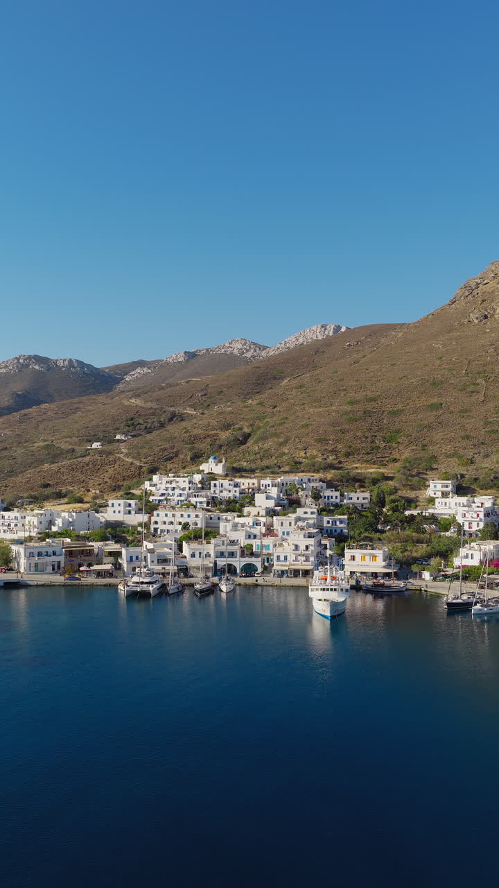 Katapola seaside village port with boats, houses and apartments on Amorgos island, Aerial, vertical