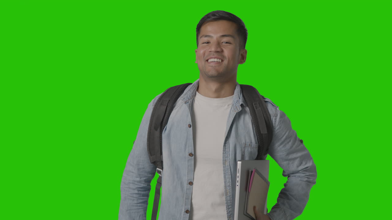 retrato de un estudiante universitario o universitario masculino sonriente con una computadora portátil contra una pantalla verde