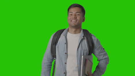 portrait of smiling male university or college student with laptop against green screen