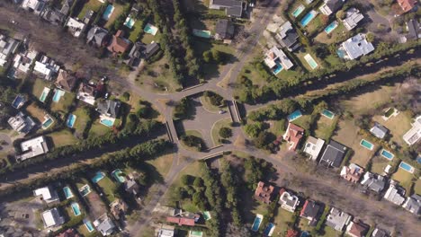 vista aérea de arriba hacia abajo en círculos ascendentes sobre una zona residencial simétrica con rotonda y casas en buenos aires, argentina