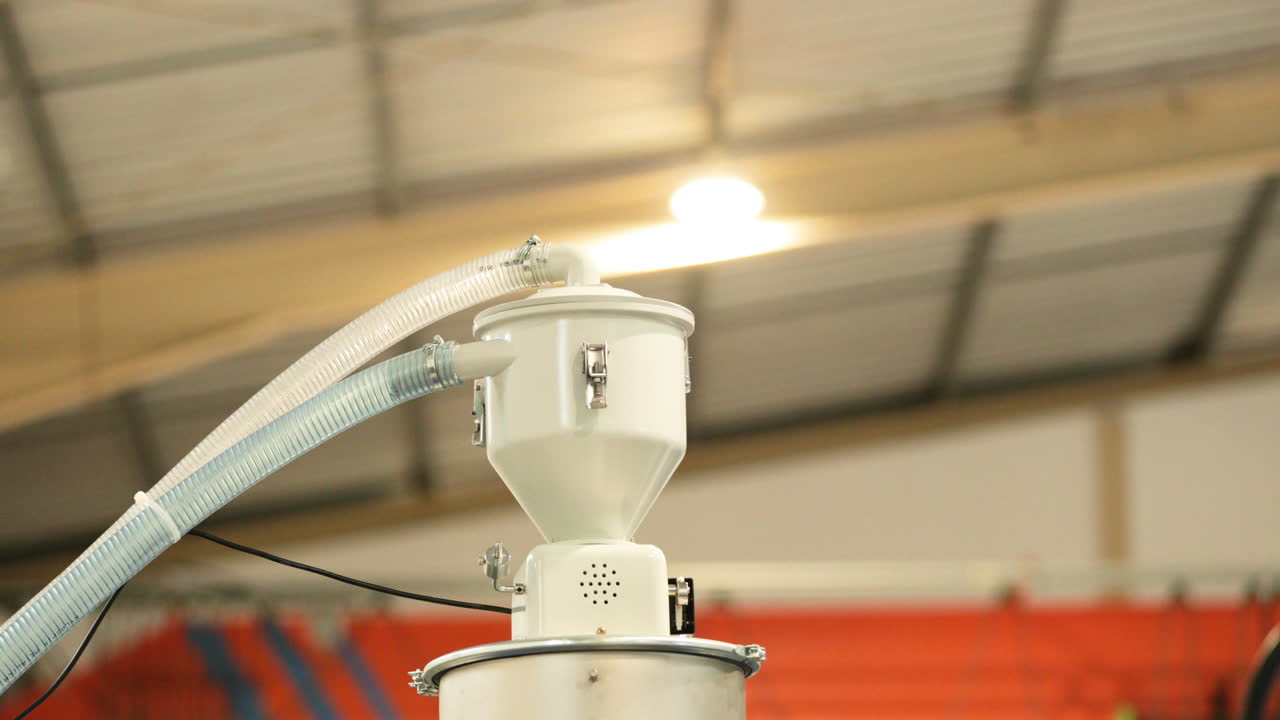 공장의 플라스틱 사출기에 연결된 호퍼 로더를 닫습니다.