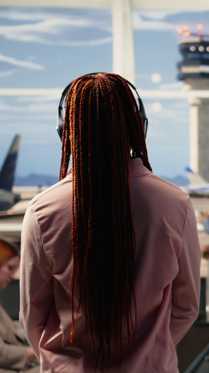 Video verticale: Adolescente afroamericana con cuffie audio in attesa di un volo internazionale.