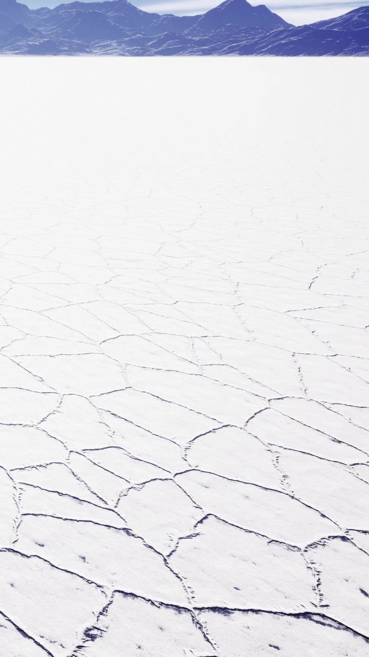 Dry salt flat with cracked surface under clear blue sky during daytime