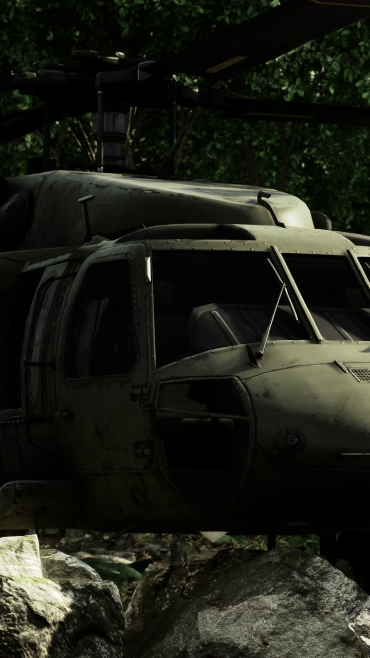 Military helicopter on rocky ground in forest setting during daytime