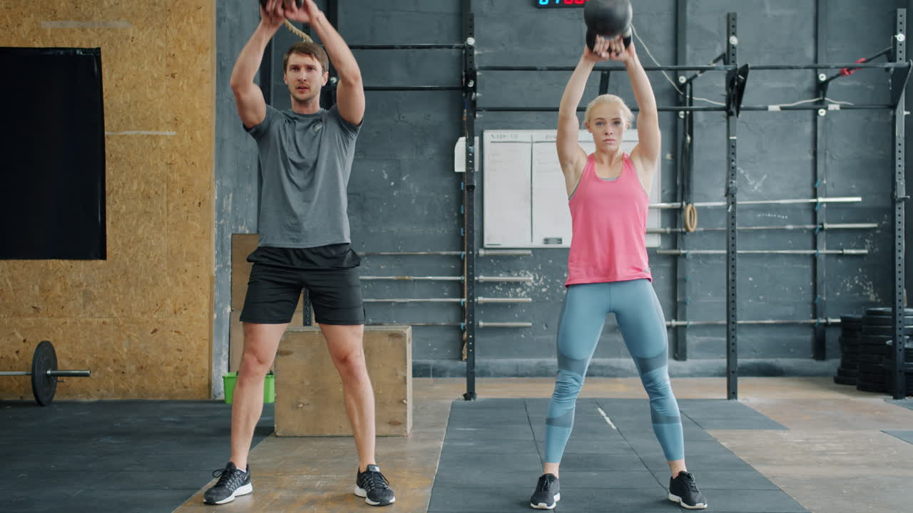 Couple Kettlebell Squats in Gym