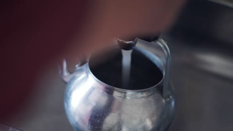 vertiendo agua en una tetera vintage y preparando todo para una taza de té verde