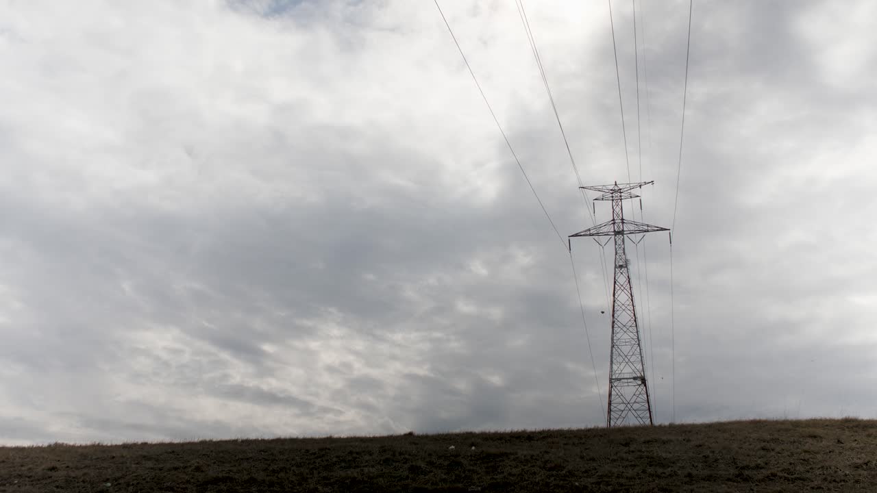 Electrical transformer tower silhouetted against a cloudy sky