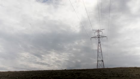 Electrical-transformer-tower-silhouetted-against-a-cloudy-sky