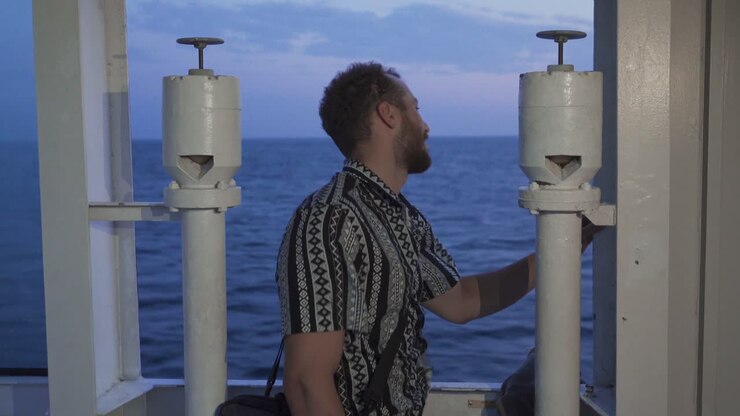 Un giovane uomo sta viaggiando sulla nave e sta guardando il mare.