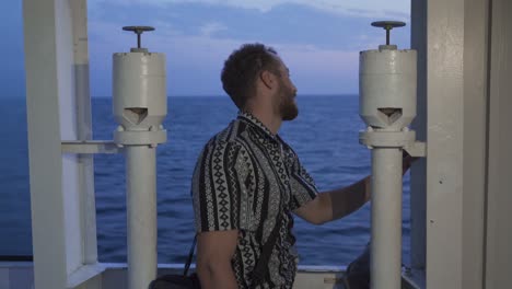 young man is traveling on the ship and looking at the sea.