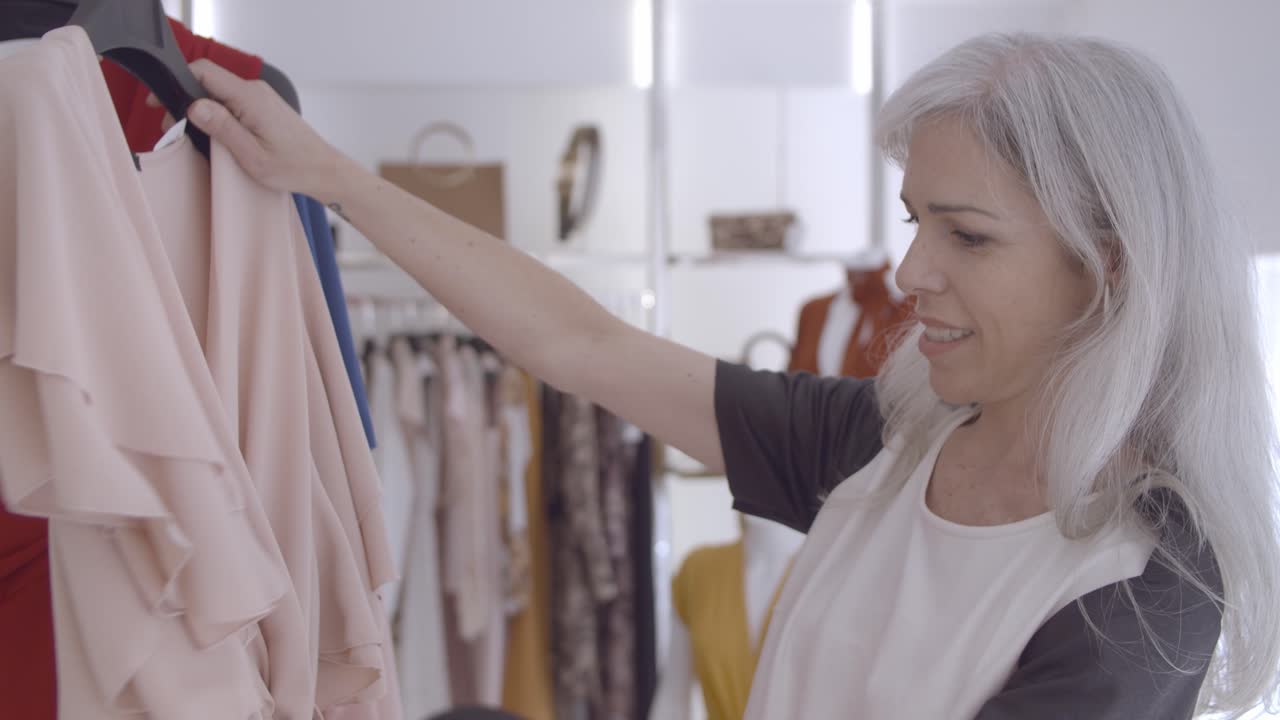 랙에 옷을 검색하는 행복한 가게 고객