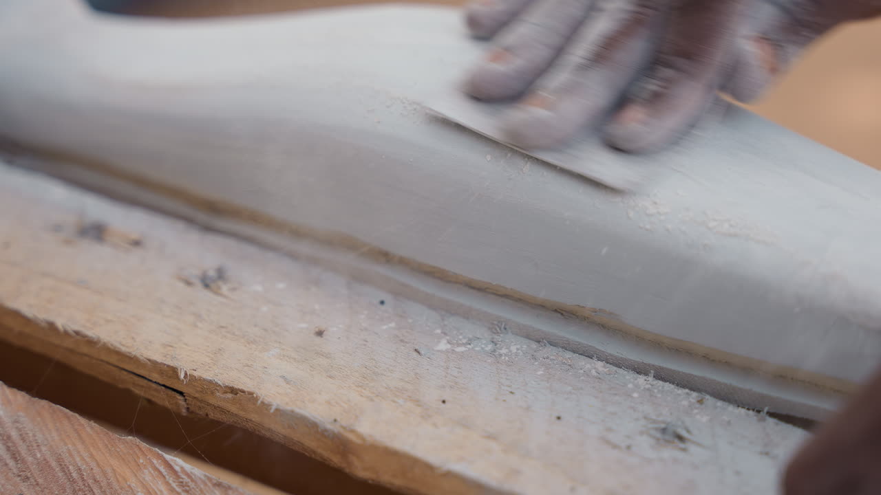 Gros plan sur le ponçage et la finition. Détails fins du traitement de surface des moulures. Processus détaillé impliquant des techniques précises de ponçage et de finition sur les moulures et les composants de garniture de meubles.