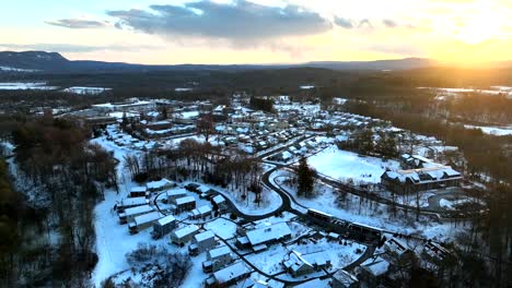 small quiet american neighborhood in winter snow. suburb houses and homes in massachusetts, america aerial backwards wide shot. woodland landscape and mountains in distance.