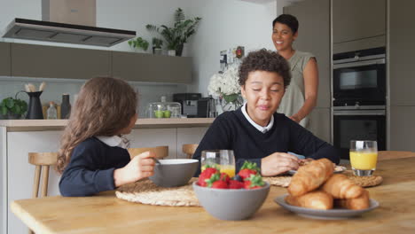 mother in kitchen helping children with breakfast before going to school