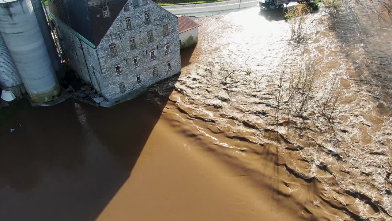 Aerial of stone mill flooded by hurricane, muddy Conestoga River in Lancaster, PA, USA