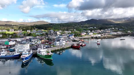 drone small fishing boat leaving castletownbere harbour ireland with large boats preparing to go to sea on a bright summer morning