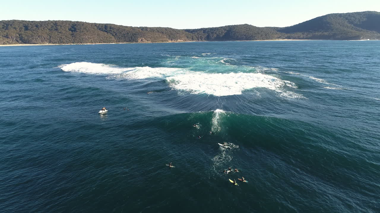 Aerial slow motion shot of surfer carving into curling wave with glowing green face