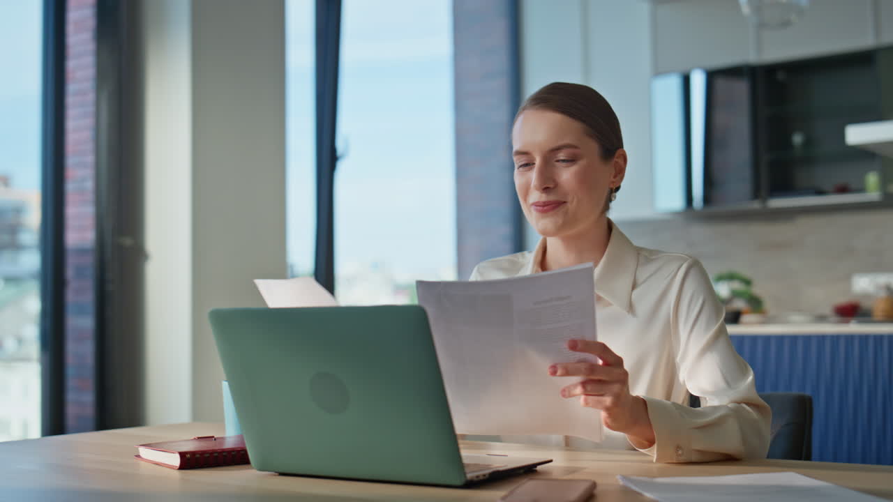 Woman accountant reviewing documents at desk with laptop closeup. Businesswoman