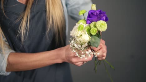 slow motion shot of hands of professional blonde female floral artist arranging beautiful bouquet at flower shot. floristry