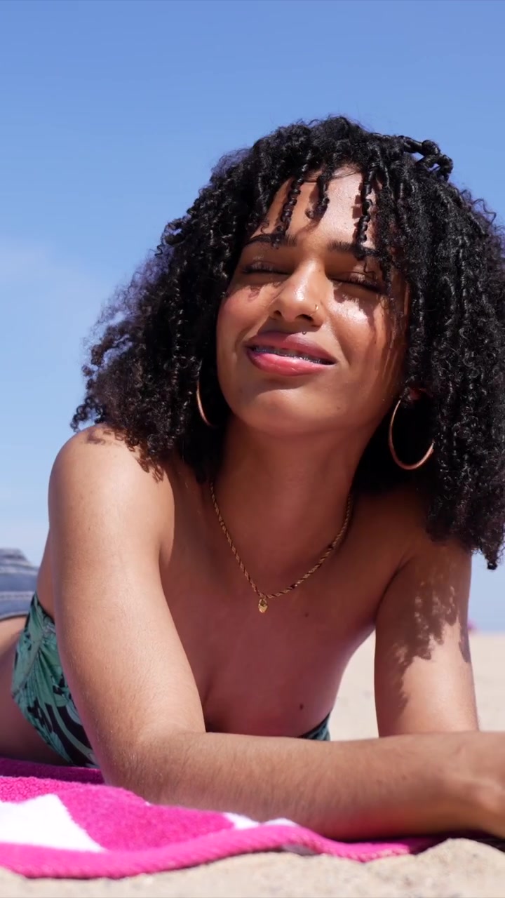 Happy Young Woman Relaxing and Sunbathing on a Sunny Beach