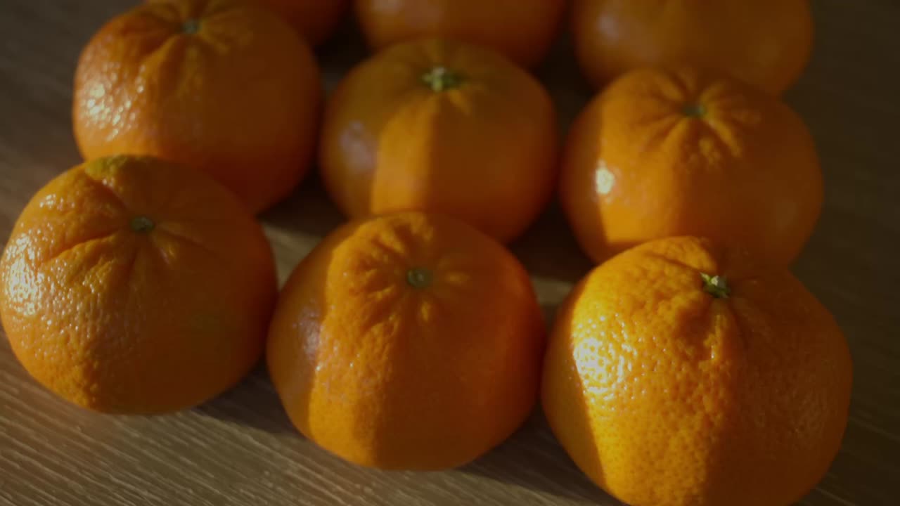 Rader med perfekte små mandarinappelsiner på et trebord i ettermiddagssolen.