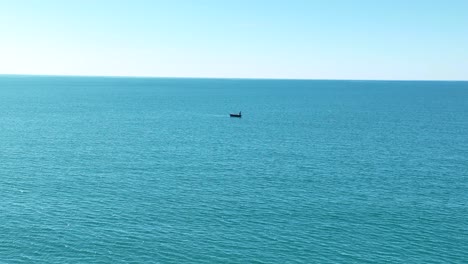 un solo barco flota en mar abierto en un día soleado azul dolly aéreo