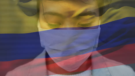 animación de una bandera colombiana ondeando contra el retrato de una mujer asiática con máscara facial en la calle
