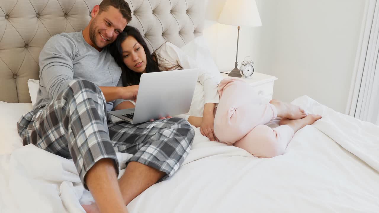 pareja romántica usando computadora portátil en la cama 4k