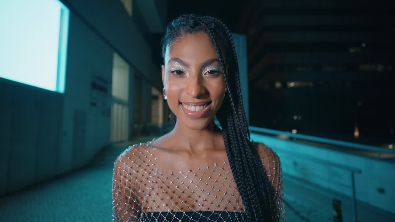 Retrato de rua noturno: morena de dreadlocks olhando para a câmera. Mulher feliz posando.
