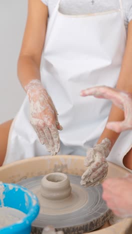hands working on a pottery wheel with clay