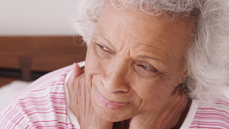 Close-Up-Of-Depressed-Senior-Woman-Looking-Unhappy-Sitting-On-Side-Of-Bed-At-Home