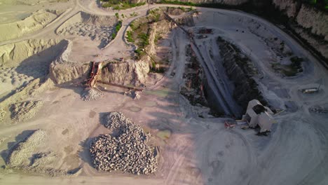 heavy-duty dump truck backing up to crusher house in quarry - mining operations and material processing