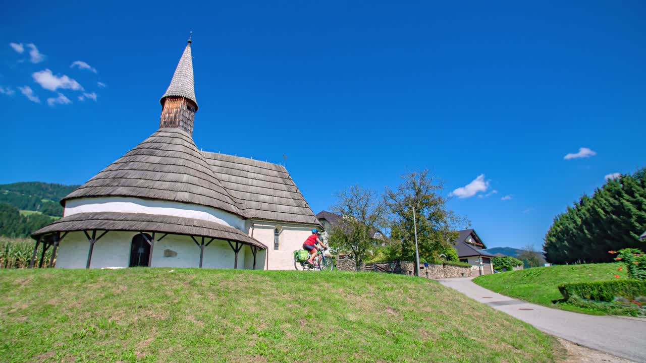 Couple cyclist passing by the unique Romanesque church Saint John the Baptist