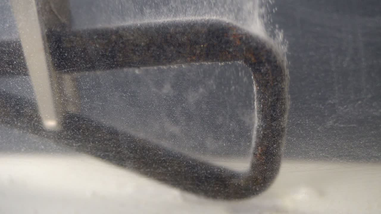 Hydrogen bubbles rise from metal undergoing electrolytic cleaning