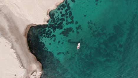 boat moving next to a cliff in a little bay of patagonia from a drone top shot sixty fps