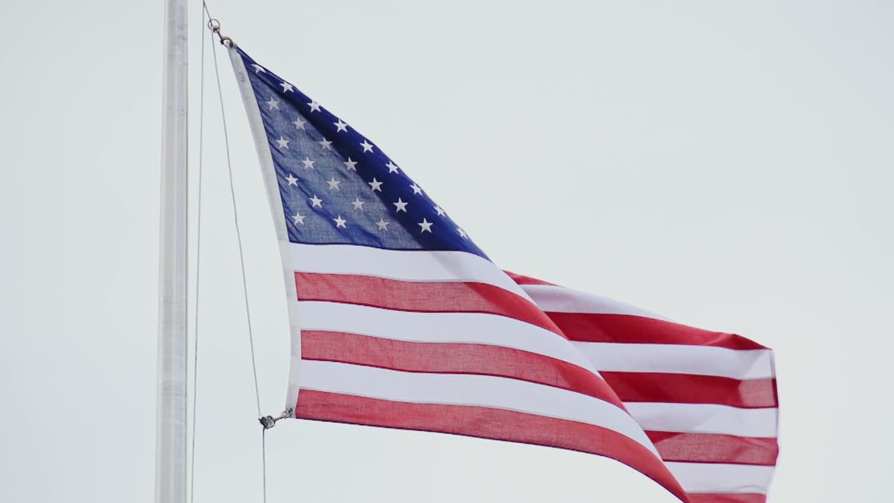 Slow motion of American flag waving, cloudy sky, symbol of freedom, resilience