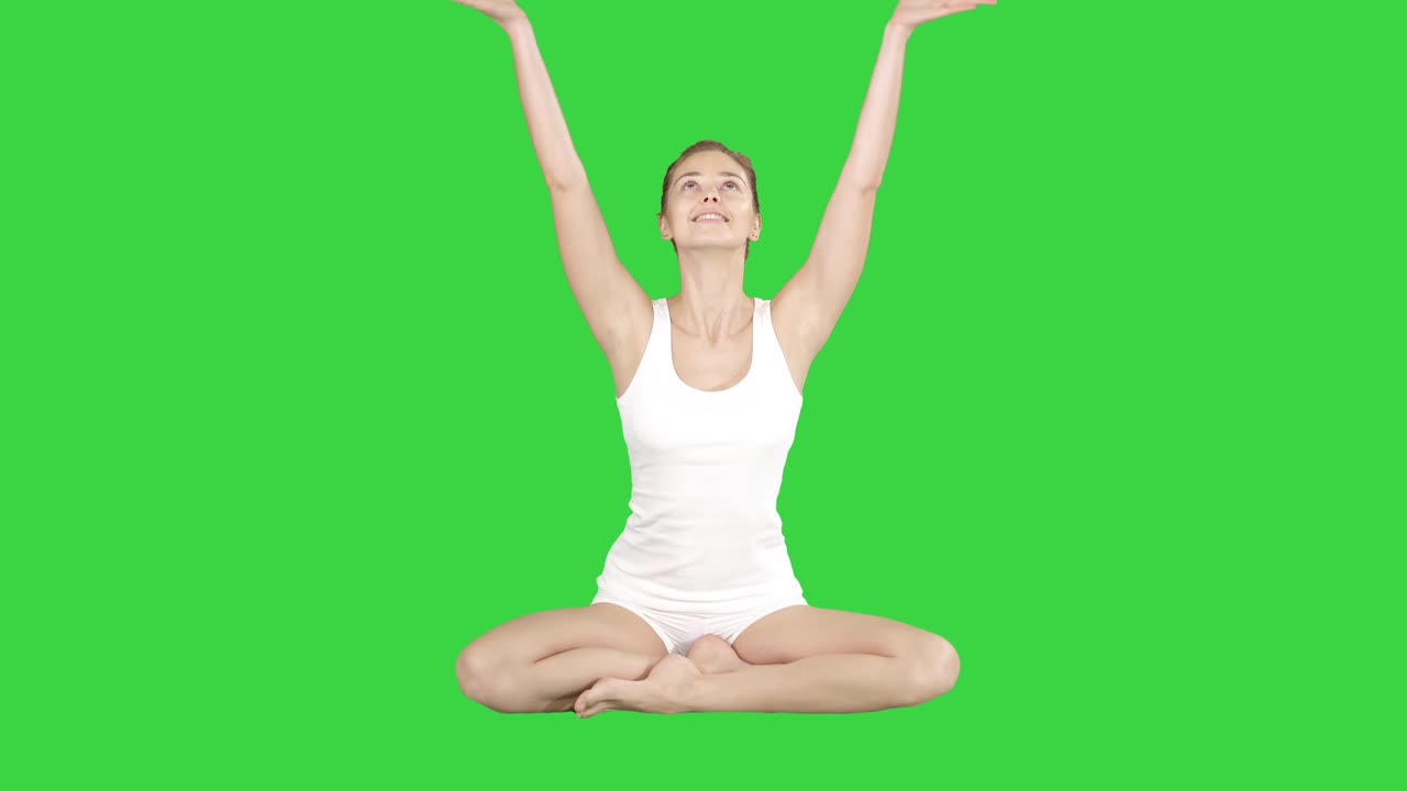 hermosa mujer sentada sin colchón de yoga en postura de loto en una pantalla verde, llave de croma