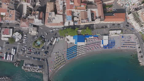 Top-down-aerial-of-the-umbrellas-and-tourists-on-the-beach-in-Amalfi,-Italy