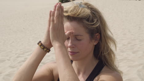 beautiful woman bringing folded hands to third eye chakra and bending forward - close up