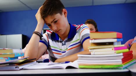 thoughtful schoolboy sitting in classroom