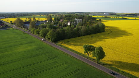 flyover over a busy local road with moving cars, green and yellow maturing fields of rapeseed and grains