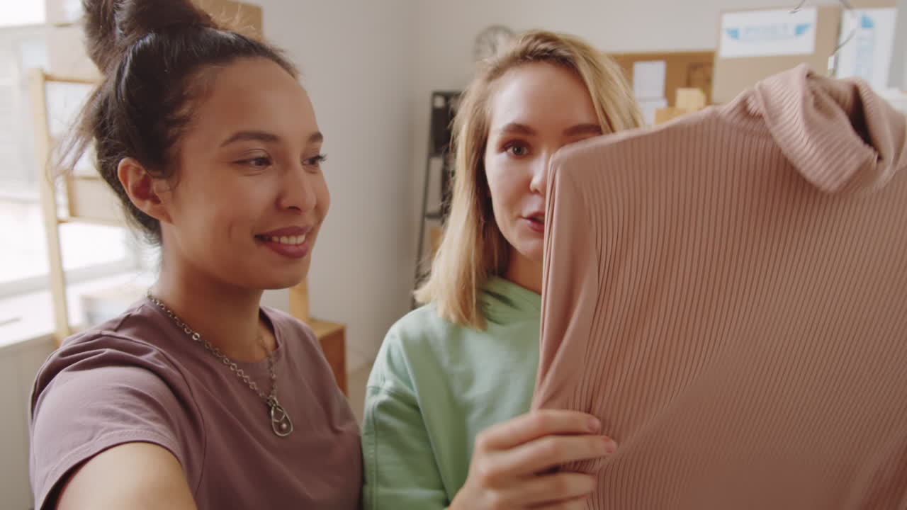 Two women shopping online, reviewing clothing item