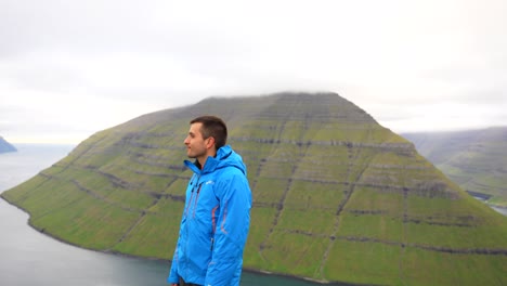 male hiker smiles at camera while enjoying the landscape at klakkur mountain, faroe islands