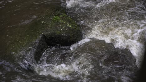 corriente del río que fluye alrededor de la roca