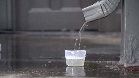 rain water from a downspout collecting into a cup slow motion at 24fps