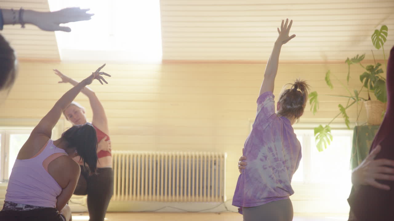 Donne in una lezione di yoga di gruppo con le braccia tese durante una posa yoga