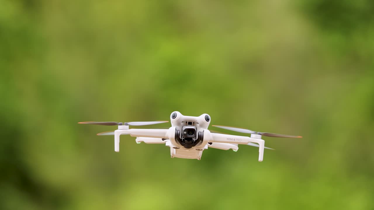 A drone smoothly flies forward against a vibrant green backdrop, showcasing its stability and precision in flight
