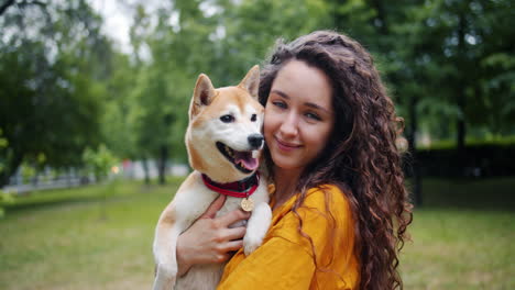 woman holding a shiba inu dog in a park