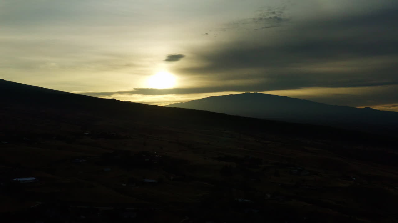silueta oscura de la montaña al atardecer con sol brillante y nubes en el cielo, dron 4k